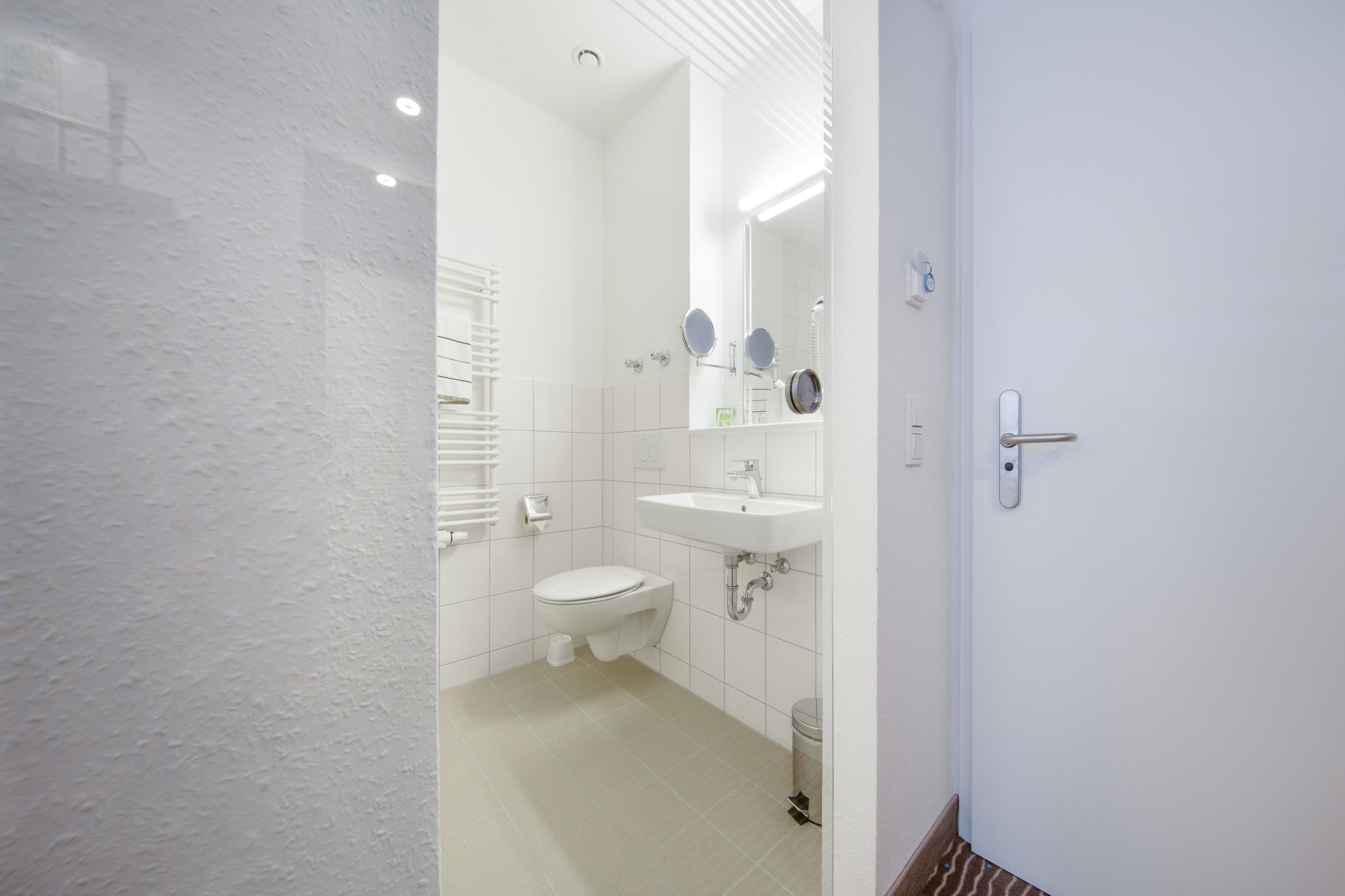 A bathroom with a toilet, sink, and mirror.