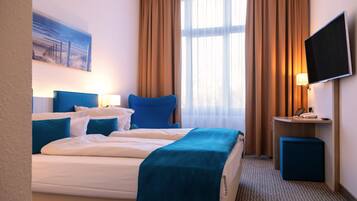 Une chambre d’hôtel avec un lit, un bureau, une télévision et une fenêtre avec des rideaux.