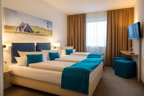 Une chambre d’hôtel avec un grand lit, deux tables de chevet, une télévision et un tableau représentant une maison accroché au mur.