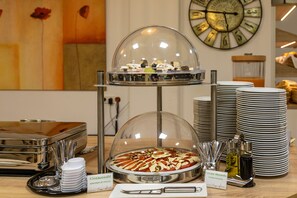 Un buffet avec une pizza couverte, des assiettes et des condiments.