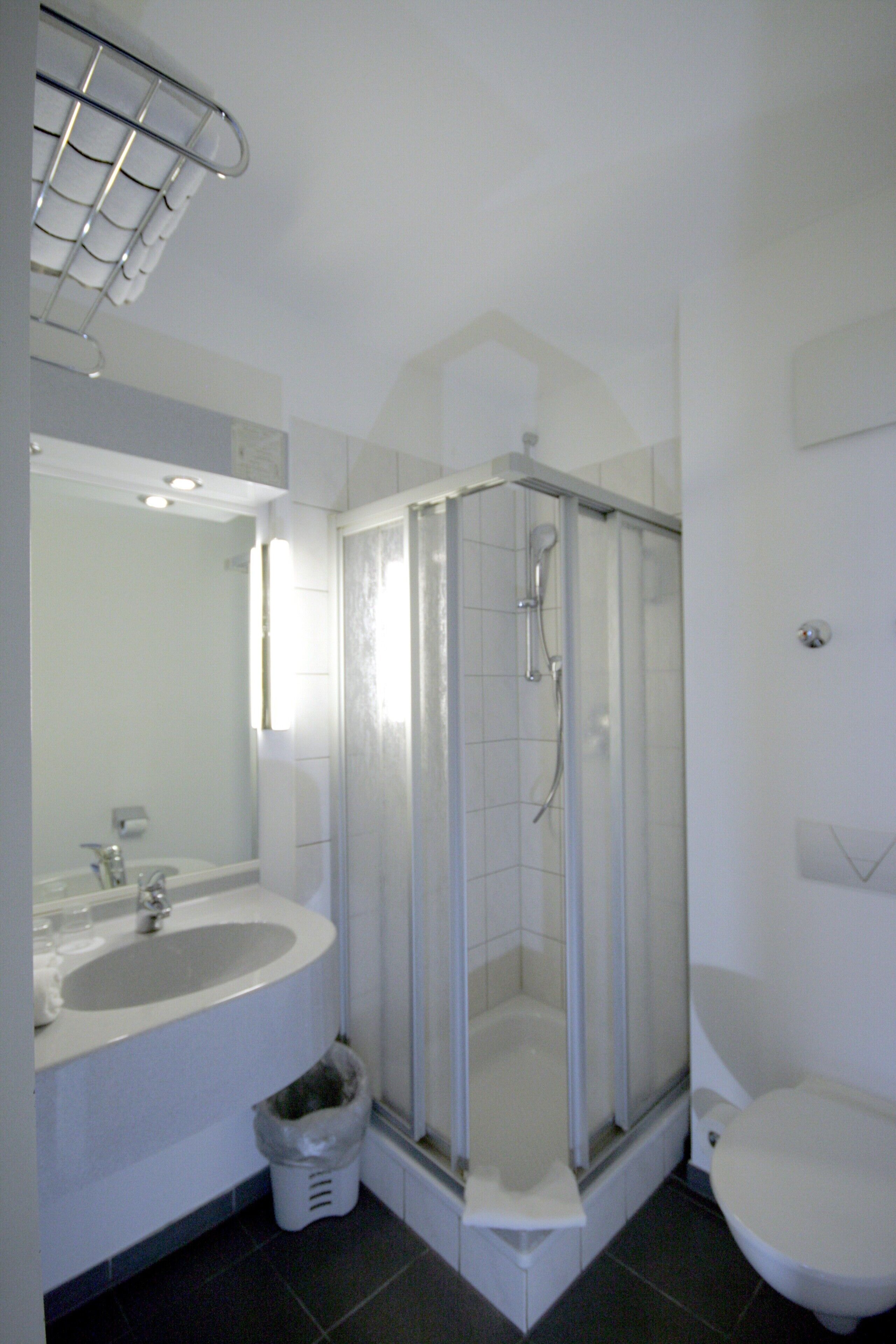 Un baño con ducha acristalada, lavabo e inodoro.