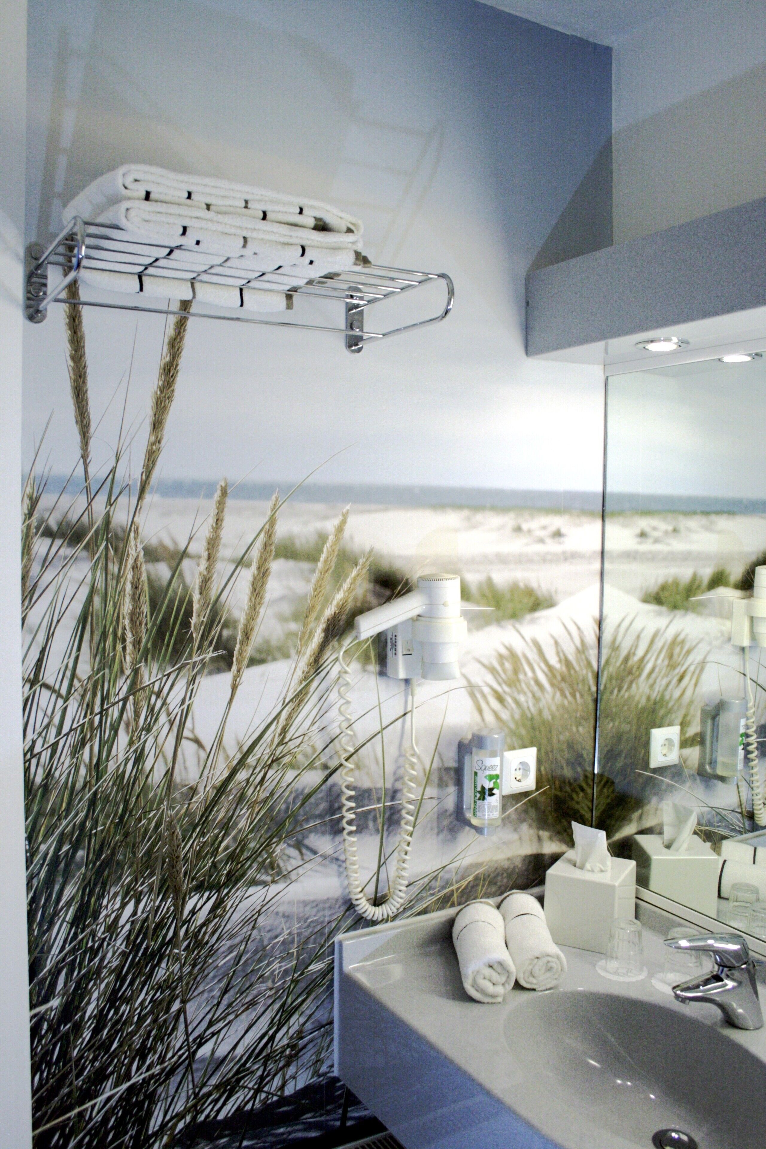 Ein Badezimmer mit Blick auf den Strand, einem Handtuchhalter und Pflegeprodukten.