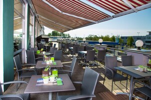 Un patio al aire libre con mesas y sillas, algunas con sombrillas.