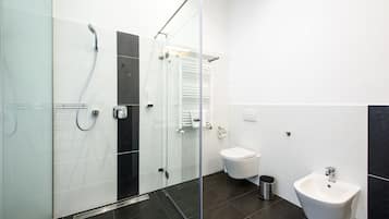 Moderni kylpyhuone, jossa on lasinen suihkuseinä, wc, bidee ja pesuallas.