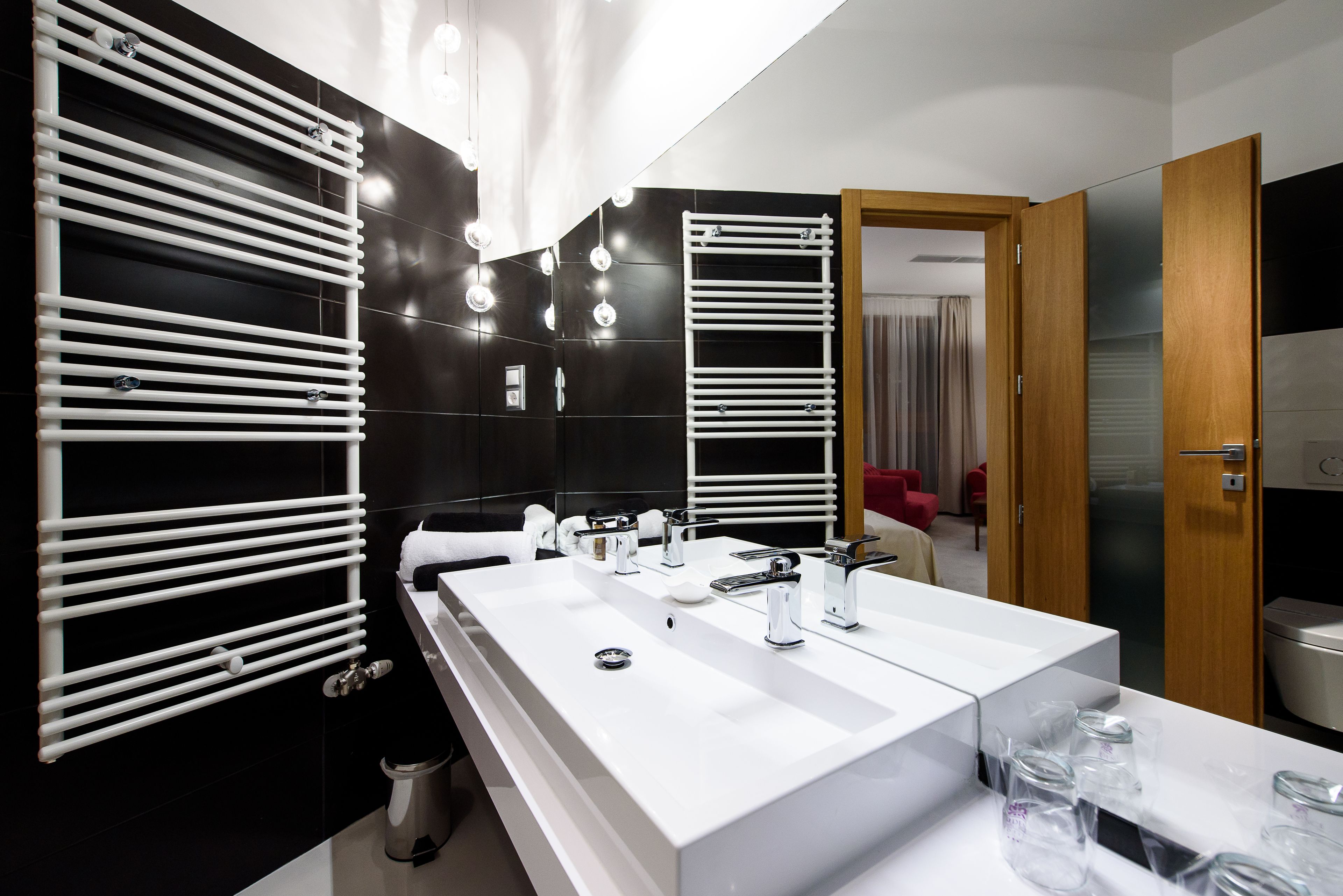 A modern bathroom with a large white sink, two mirrors, and a towel rack.