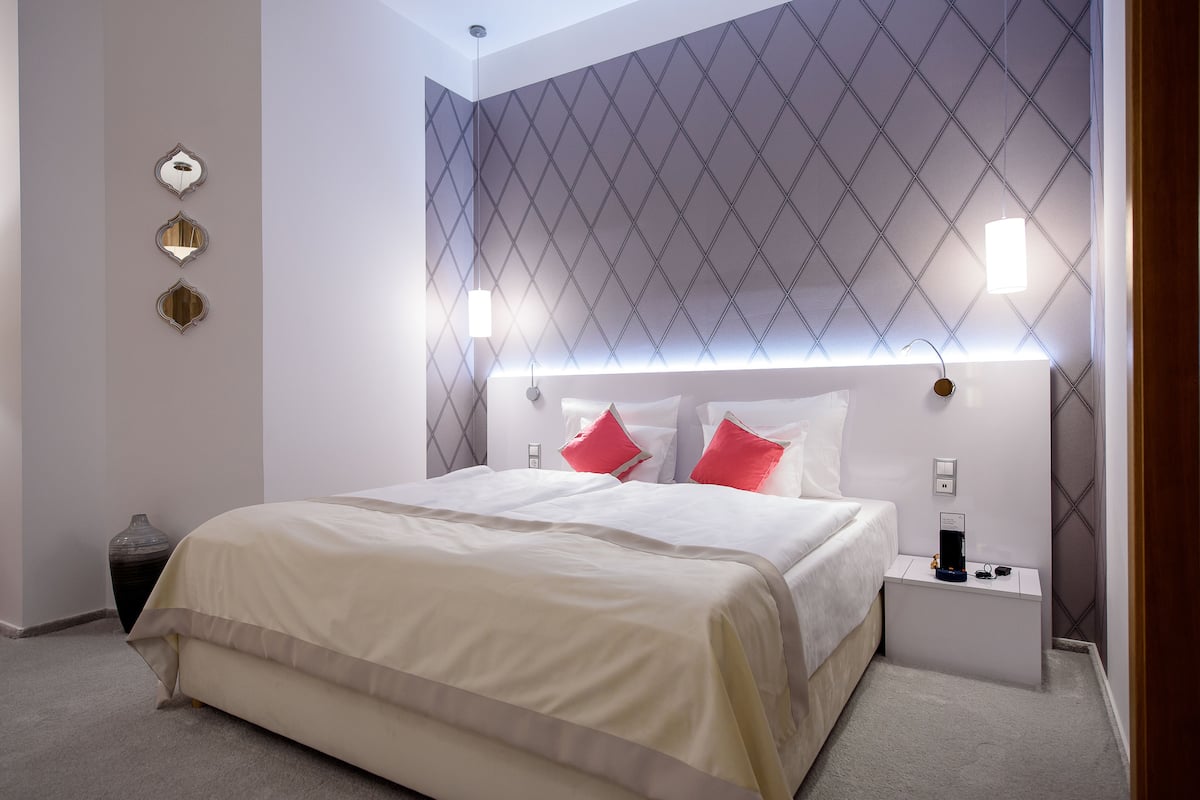 Ein modernes Hotelzimmer mit einem großen Bett, Nachttischen und einer dekorativen Wandverkleidung.