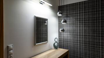 Ein Badezimmer mit einem Holzwaschtisch, einem Spiegel, einer Wandleuchte und einer Wand mit Muster.