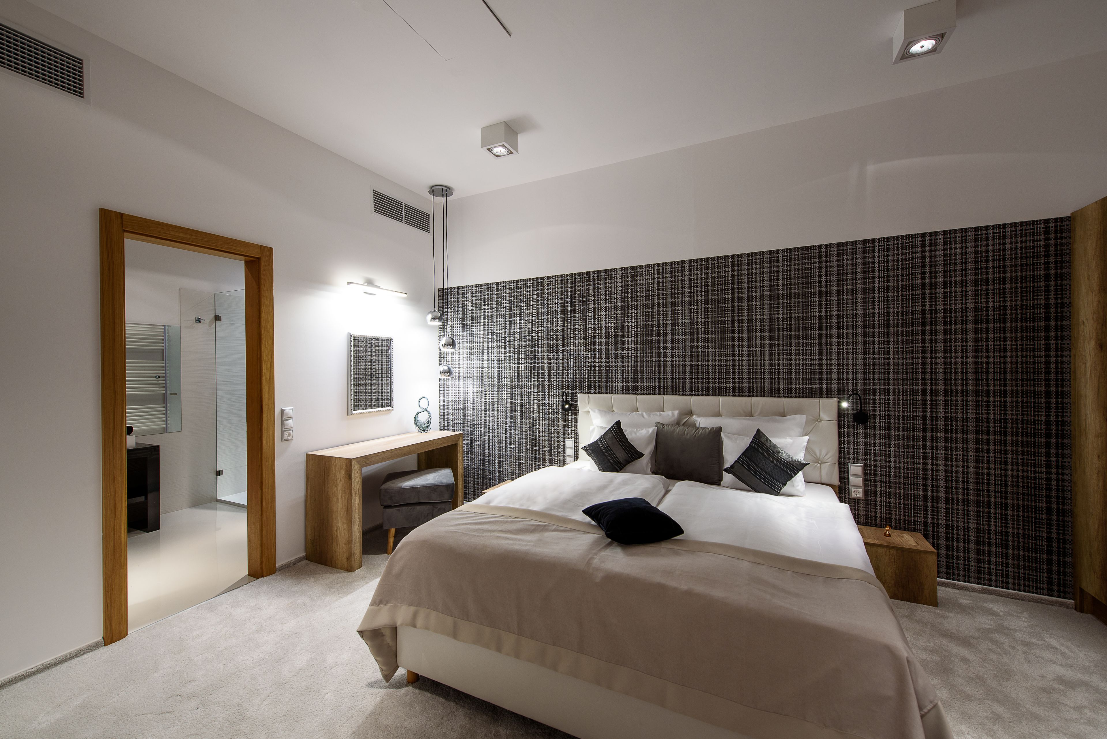 Ein modernes Schlafzimmer mit einem großen Bett, einem Nachttisch, einem Schreibtisch und einem Spiegel.
