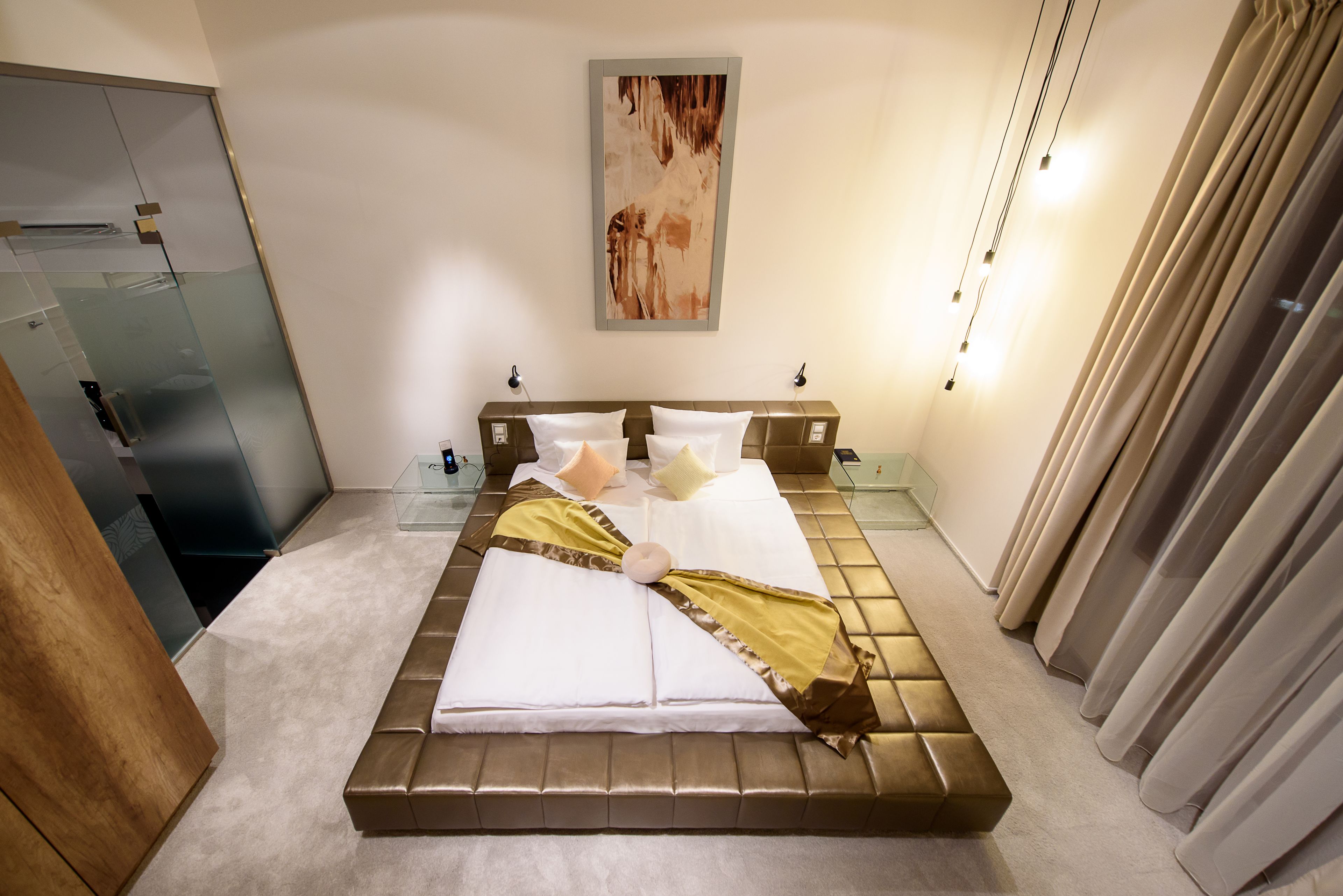 Una cama con ropa de cama dorada y blanca, un cabecero de madera y lámparas de noche.