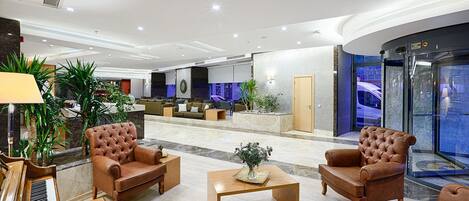 Un vestíbulo moderno con sillones de cuero, un piano y una recepción.