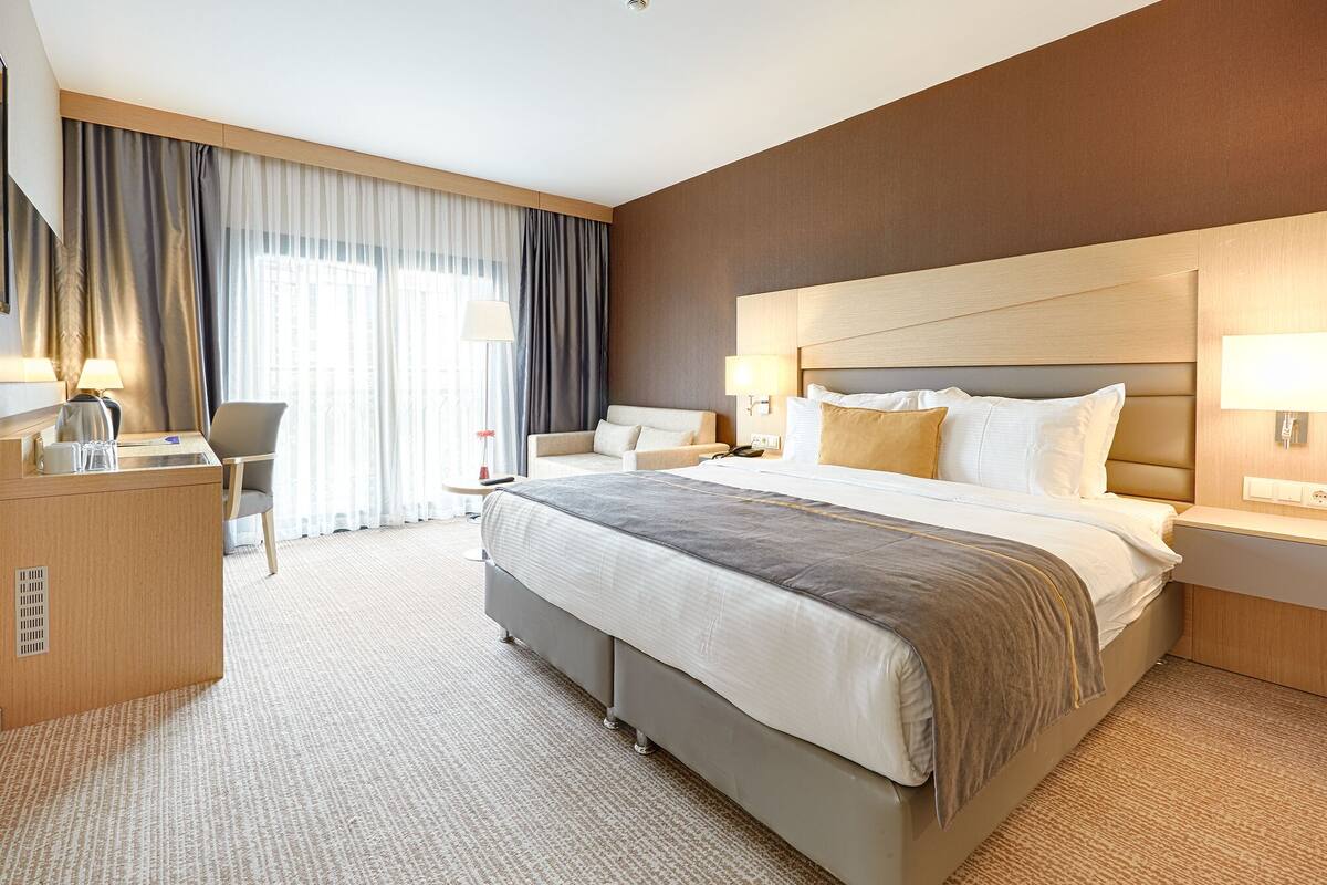 Ein Hotelzimmer mit einem großen Bett, Nachttischen, einem Schreibtisch und einem Stuhl.