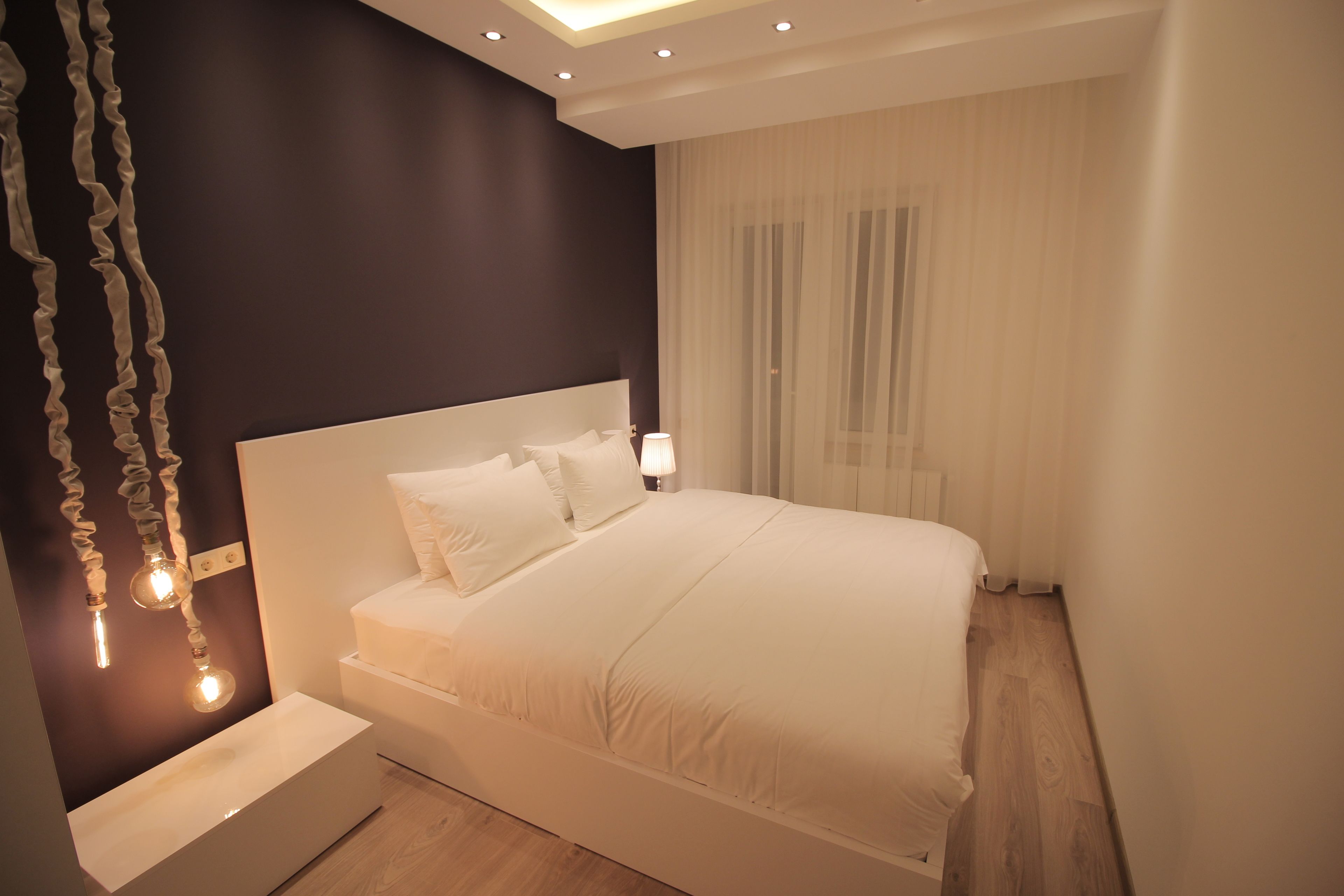 Un dormitorio moderno con una cama grande, lámparas de noche y una lámpara colgante original.