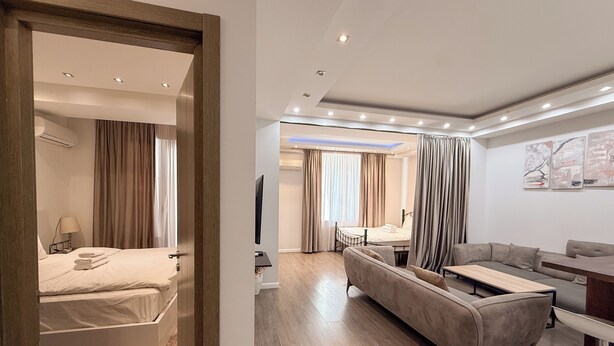 Quarto de hotel moderno com cama, sofá, escrivaninha e televisão.