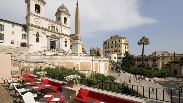 Une terrasse sur le toit, dotée d’un espace extérieur aménagé, offrant une vue sur un bâtiment historique avec un clocher et un obélisque.