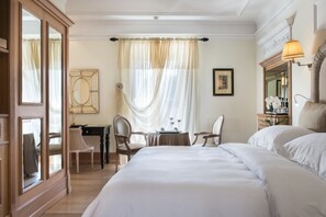 A hotel room with a large bed, a desk with a chair, a small table with a chair, and a large mirror. - Il Palazzetto (Rome)