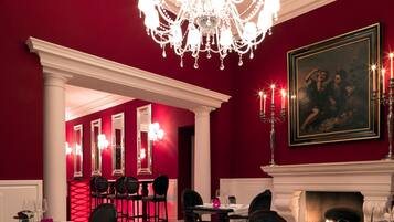 Uma sala de jantar formal com lustre, paredes vermelhas e lareira.