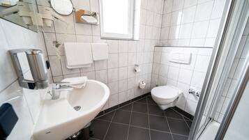 A modern bathroom with a white sink, mirror, and toilet.