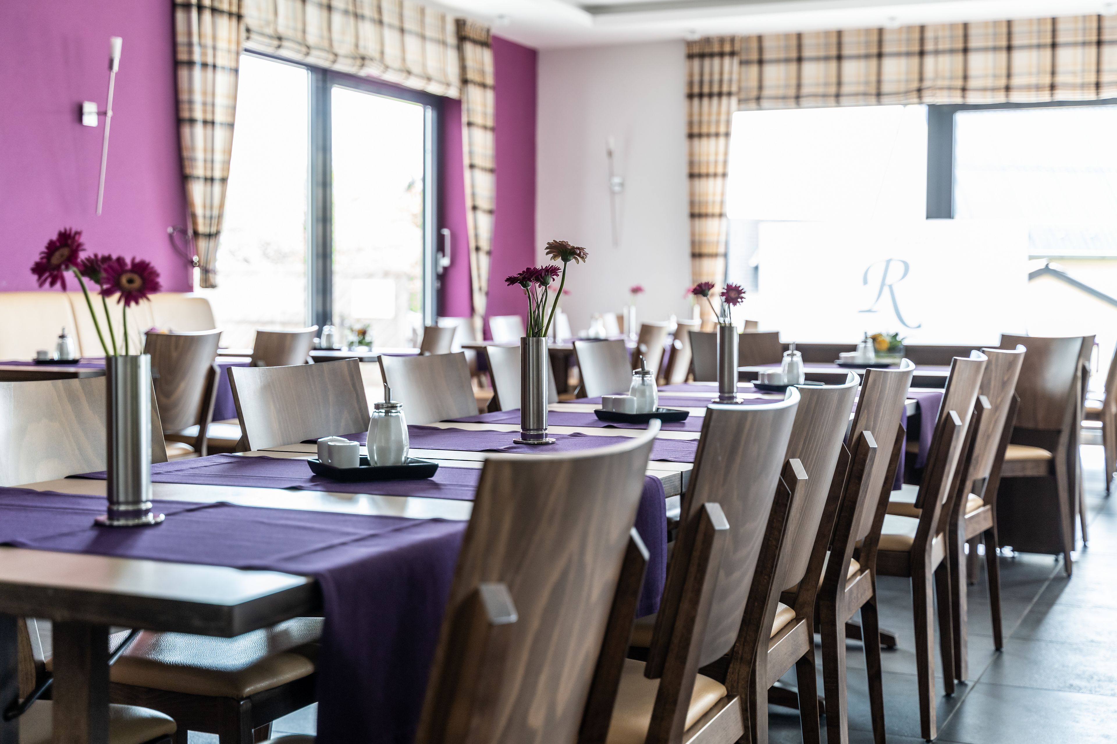 Ein Essbereich mit violetten Tischdecken, Holzkästen und Vasen mit Blumen.