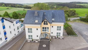 Een hotel met een blauw betegeld dak, een centrale trap en een parkeerplaats.