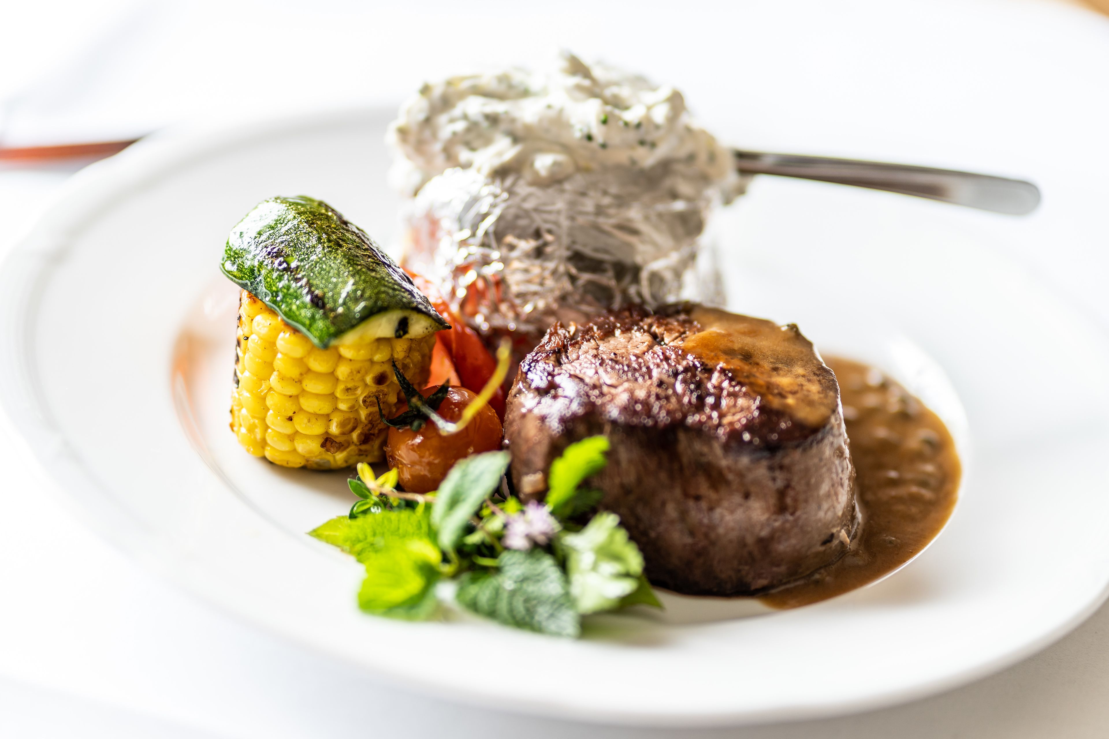 Ein Teller mit einem Steak, Mais und Kartoffelpüree.