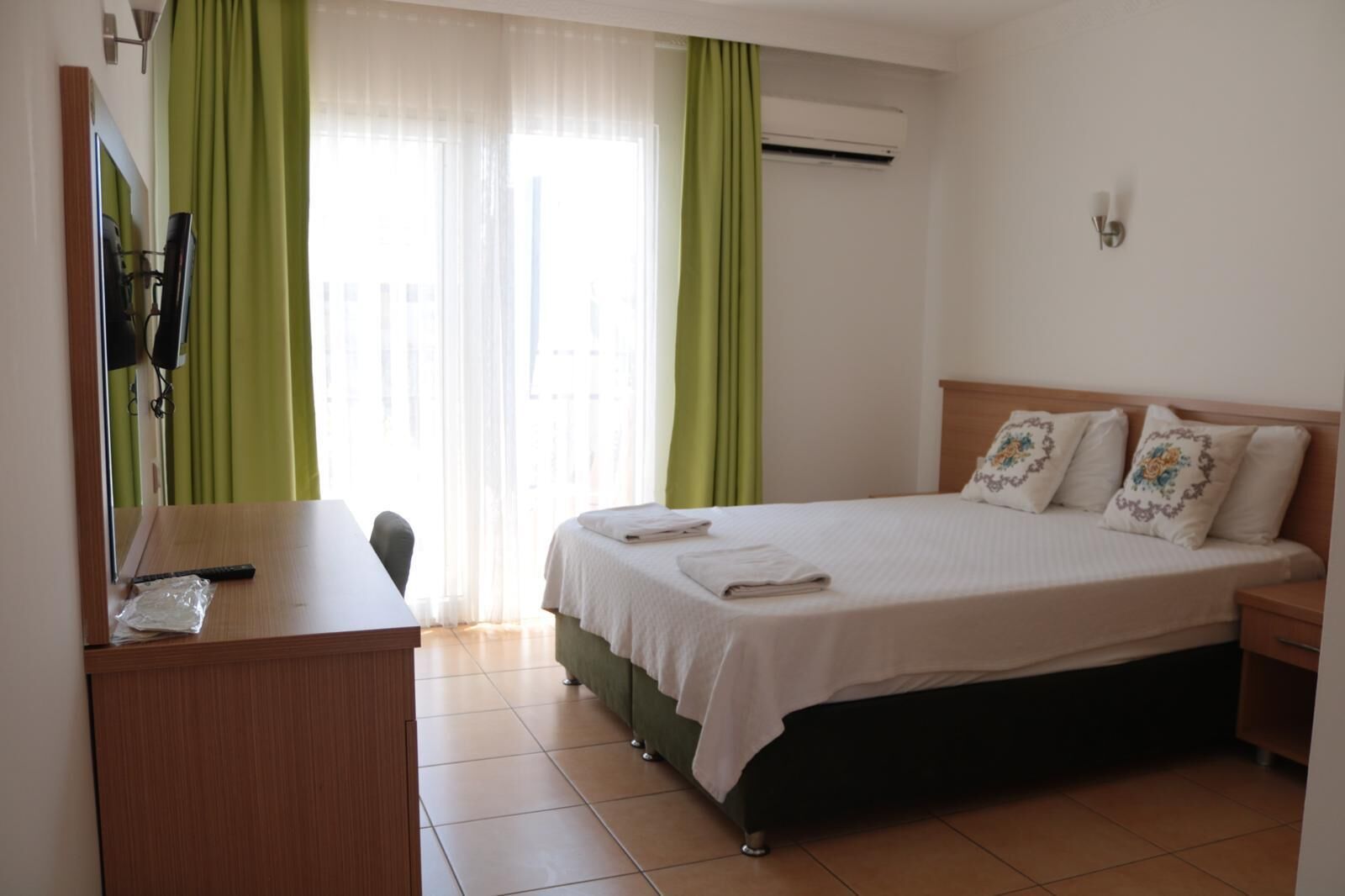 A hotel room with a bed, a desk, a chair, and a TV.