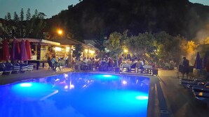 A pool area with a dining setup and a bar. - Taner Otel (Fethiye)