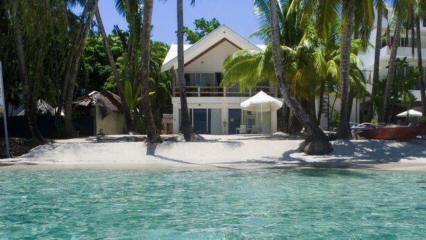 A beachfront hotel with a clear view of the ocean, palm trees, and a sandy beach. - Mabuhay Beach House (Boracay Island)