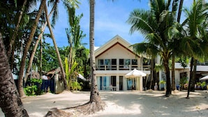 A beachfront property with a two-story building, palm trees, and a sandy beach. - Mabuhay Beach House (Boracay Island)