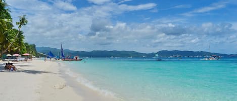 On the beach, white sand, sun-loungers, beach umbrellas