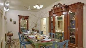 A dining room with a long wooden table set for a meal, surrounded by blue chairs. - French Haveli (Ahmedabad)
