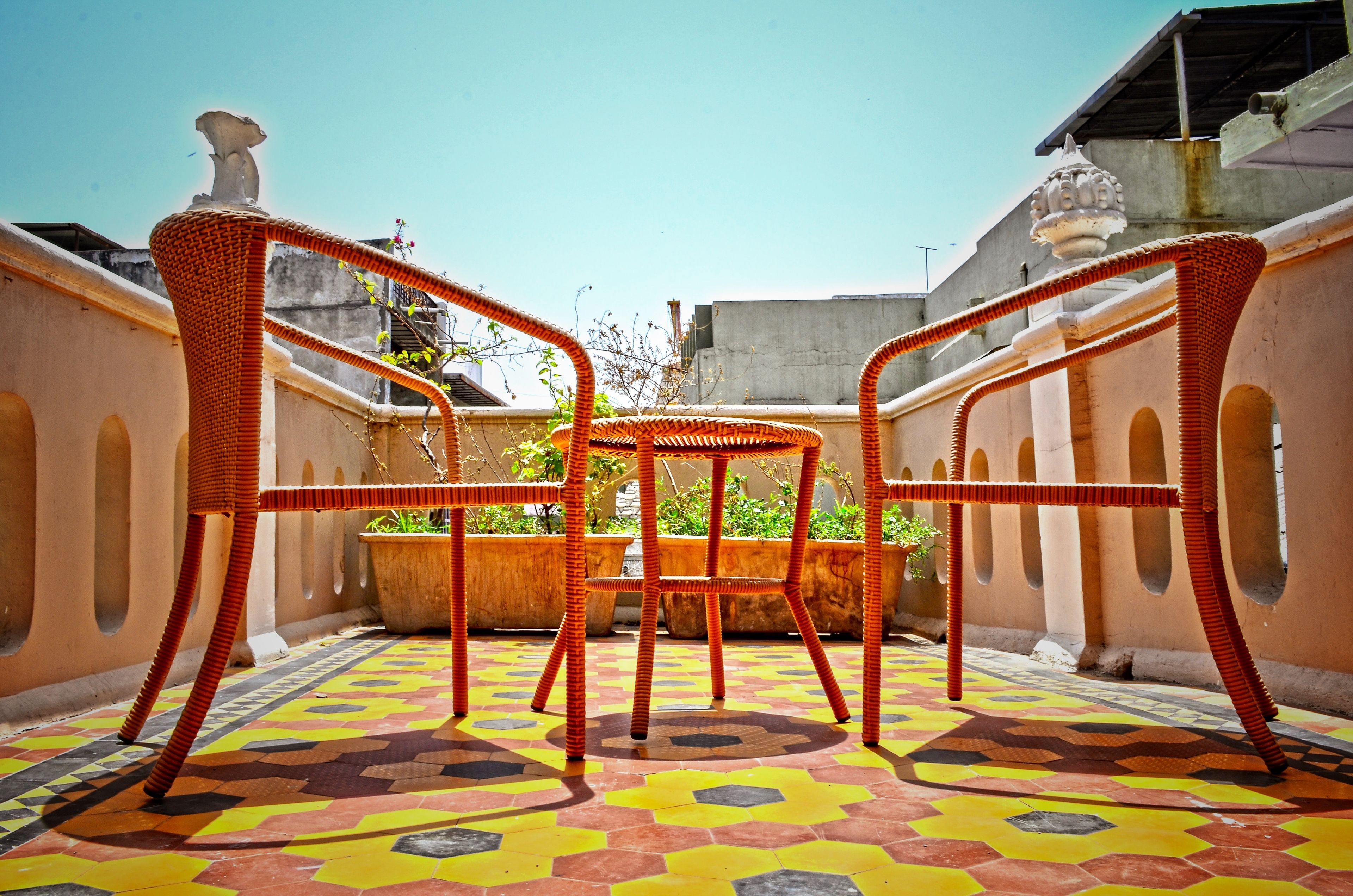 A patio with a patterned floor, a table, and two wicker chairs.