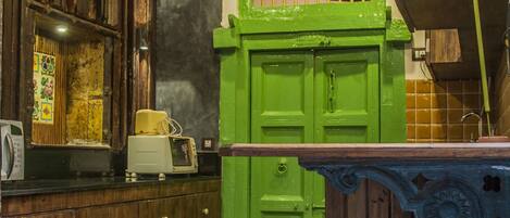 Una cocina con armarios de madera, una puerta verde y una lámpara de techo blanca.