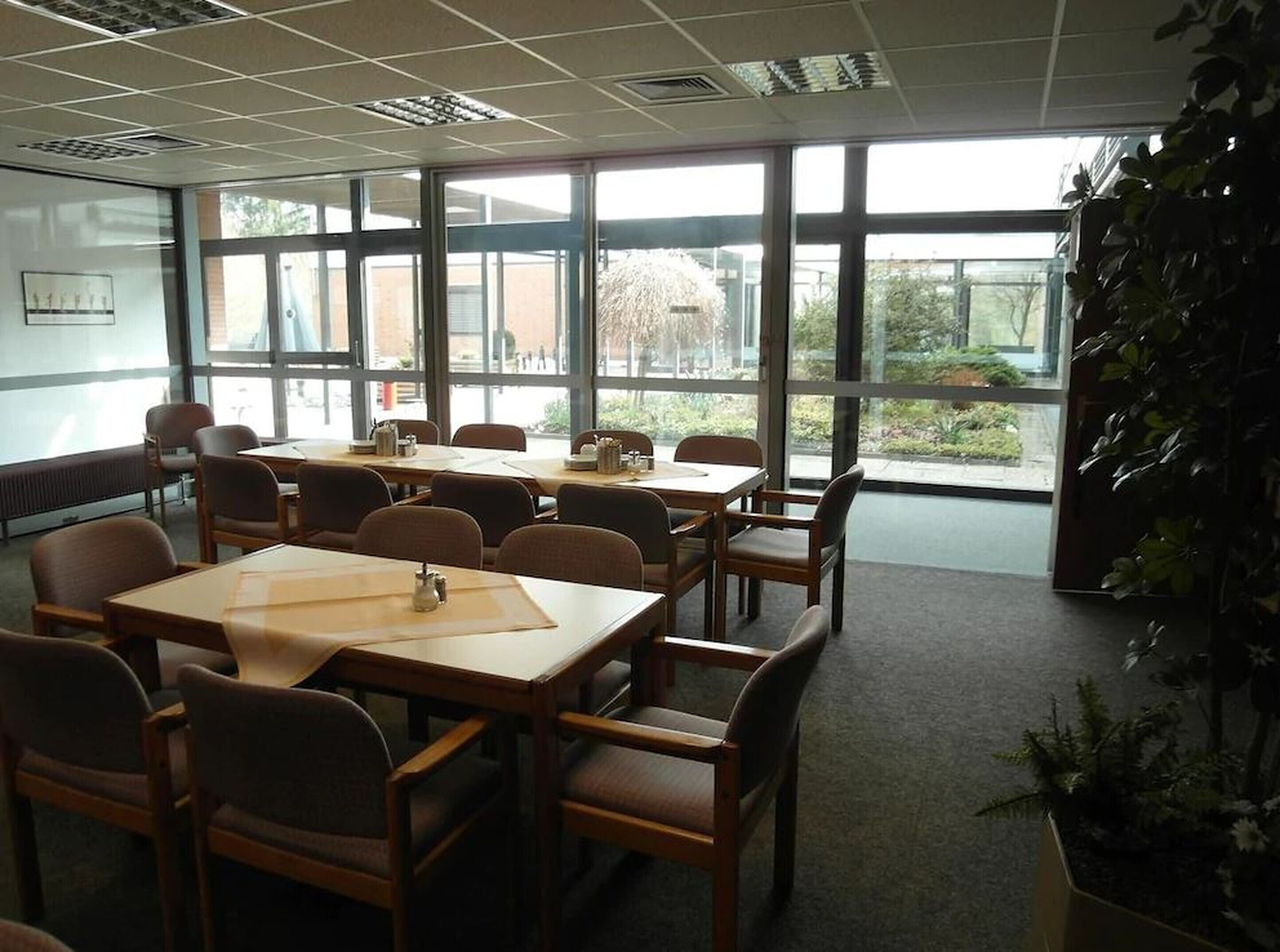 Un salón de conferencias con ventanas amplias, mesas y sillas de madera.