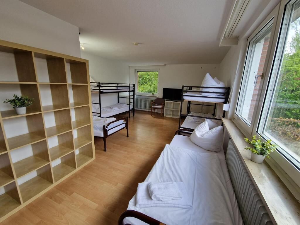 Quarto com beliches, escrivaninha, cadeira e estante.