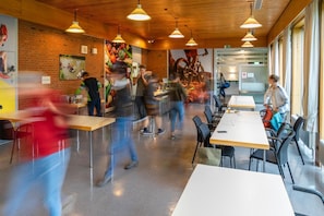 A modern dining area with wooden ceiling, glass partitions, and multiple tables.