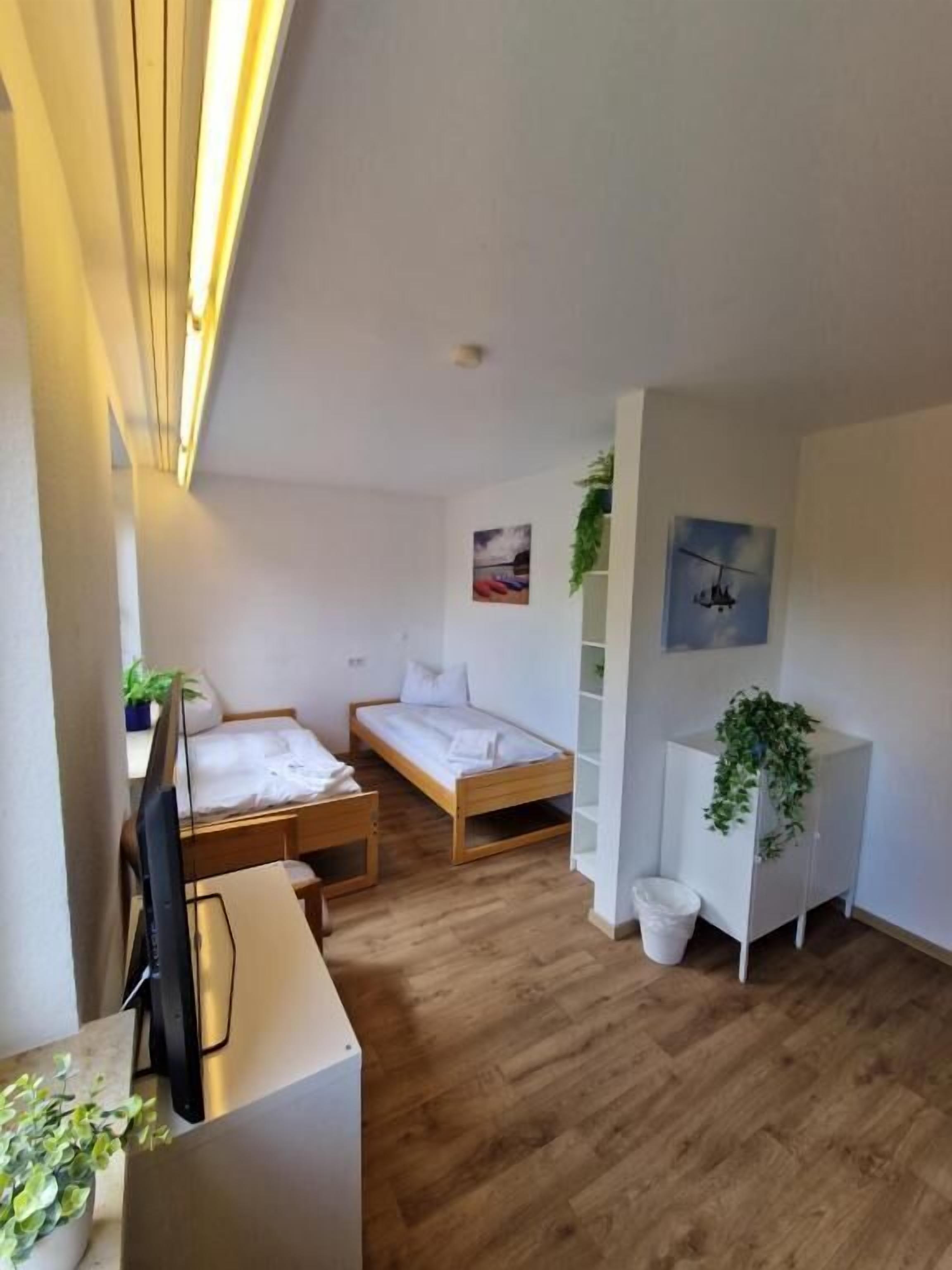 Ein kleines Zimmer mit einem Bett, einem Schreibtisch und einer kleinen Pflanze.