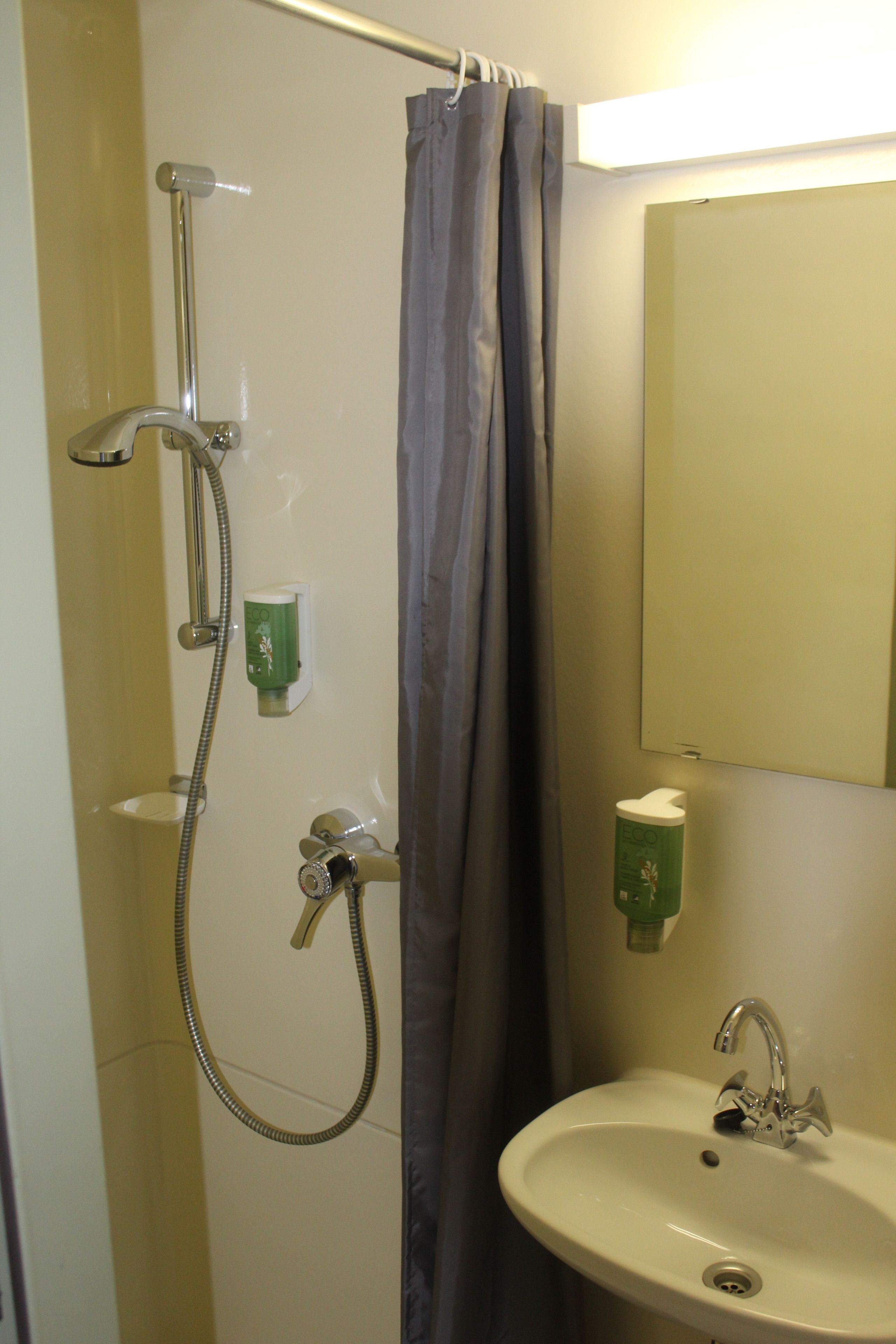 Ein Badezimmer mit Dusche, Waschbecken und Spiegel.