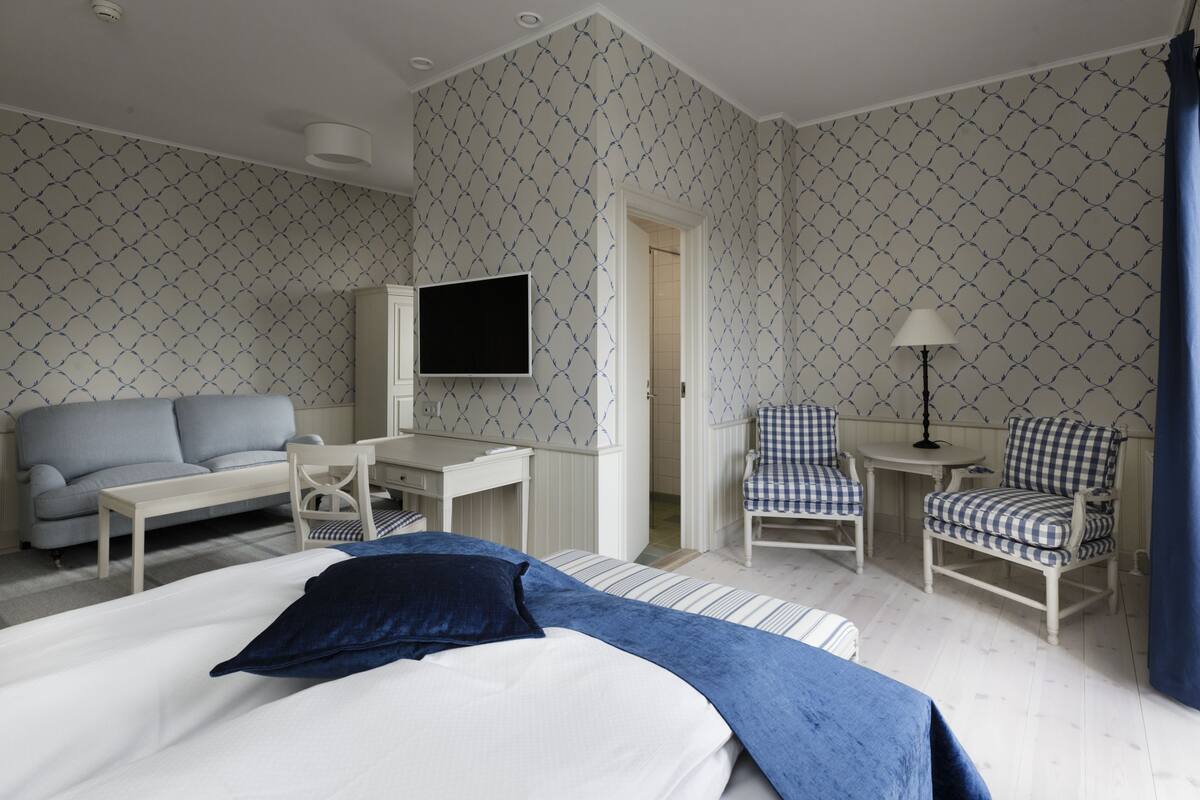 Une chambre d’hôtel avec un lit, un bureau, une chaise, une télévision et une lampe.