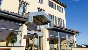 A modern hotel with a large glass entrance, multiple floors, and a flat roof.