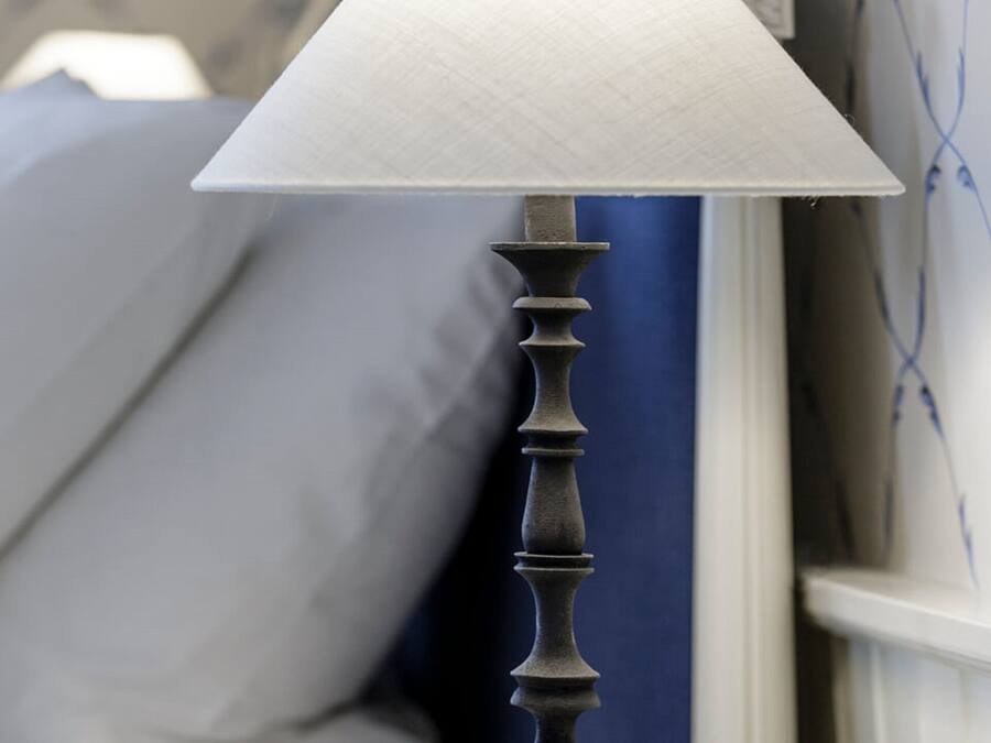 A table lamp with a textured lampshade on a bedside table.