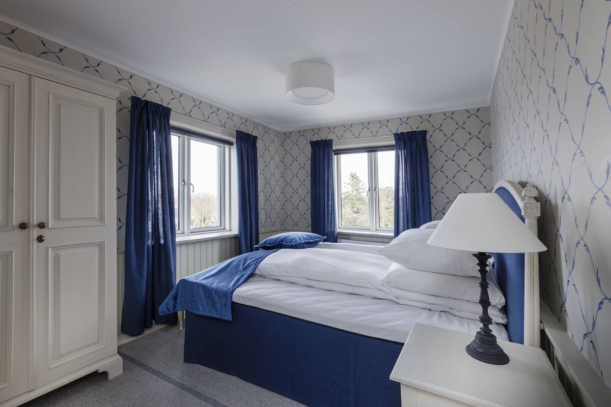 Une chambre à coucher avec un lit, une table de chevet, une lampe et une armoire.