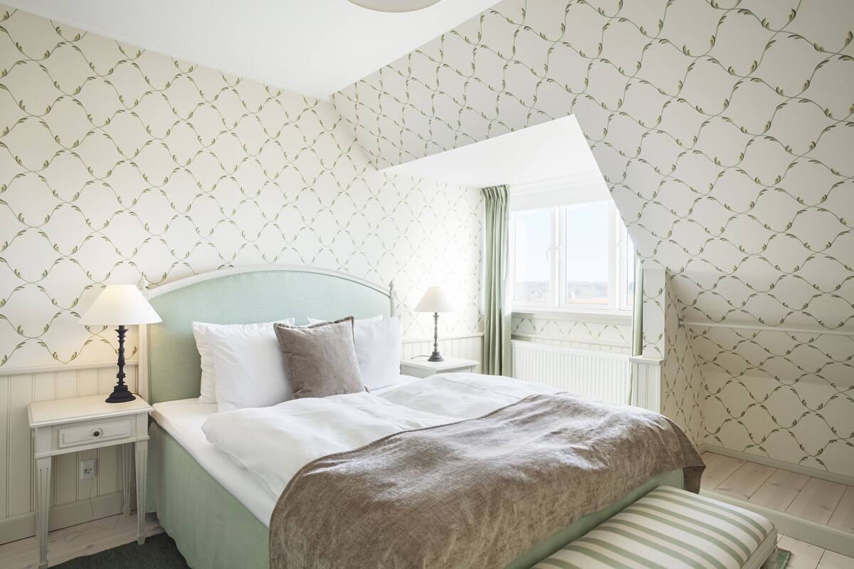 Une chambre à coucher bien rangée, avec un lit, des tables de chevet et une fenêtre.