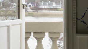 A view from a window with a balustrade, overlooking a body of water and houses in the distance.