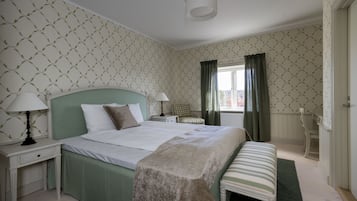 Une chambre bien rangée, avec un lit, des tables de chevet, un banc et une fenêtre avec des rideaux.