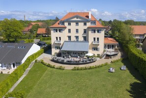 A multi-story building with a central courtyard, balconies, and a covered outdoor seating area. - Hotel Bretagne (Hornbaek)