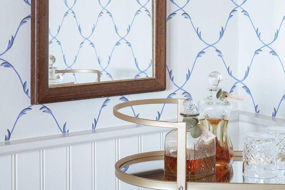 Une salle de bain avec un miroir, un radiateur blanc et un chariot à boissons contenant de la verrerie et des bouteilles.