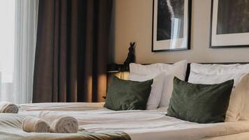 Una habitación de hotel con cama, almohadas, lámpara y cortinas.