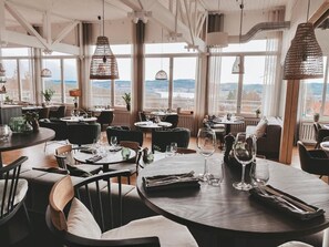 Un restaurante con mesas redondas, sillas e lámparas colgantes.