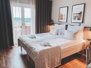 Habitación de hotel con una cama grande, vista a través de una puerta de vidrio y dos cuadros en la pared.