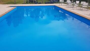 Una piscina al aire libre de temporada, sombrillas